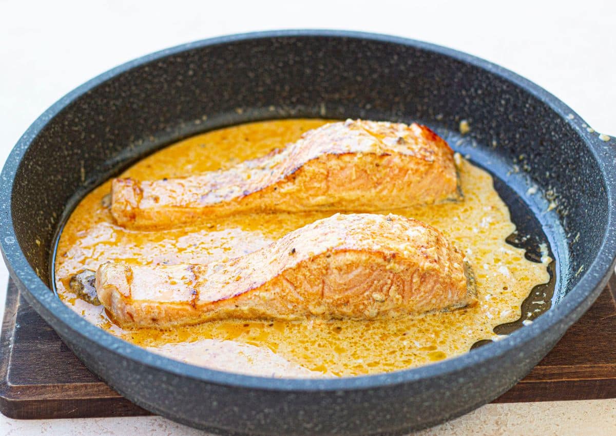 salmon in skillet in sauce