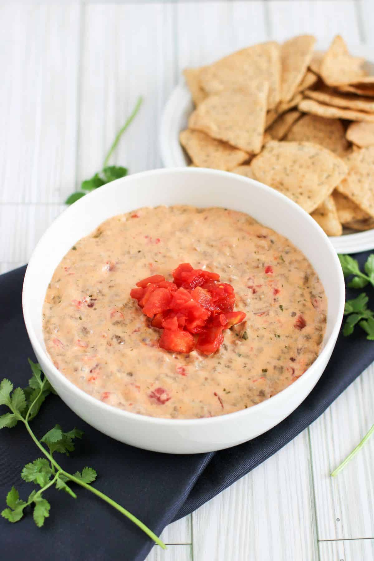 Beef Con Queso Dip in a bowl with tomates on top