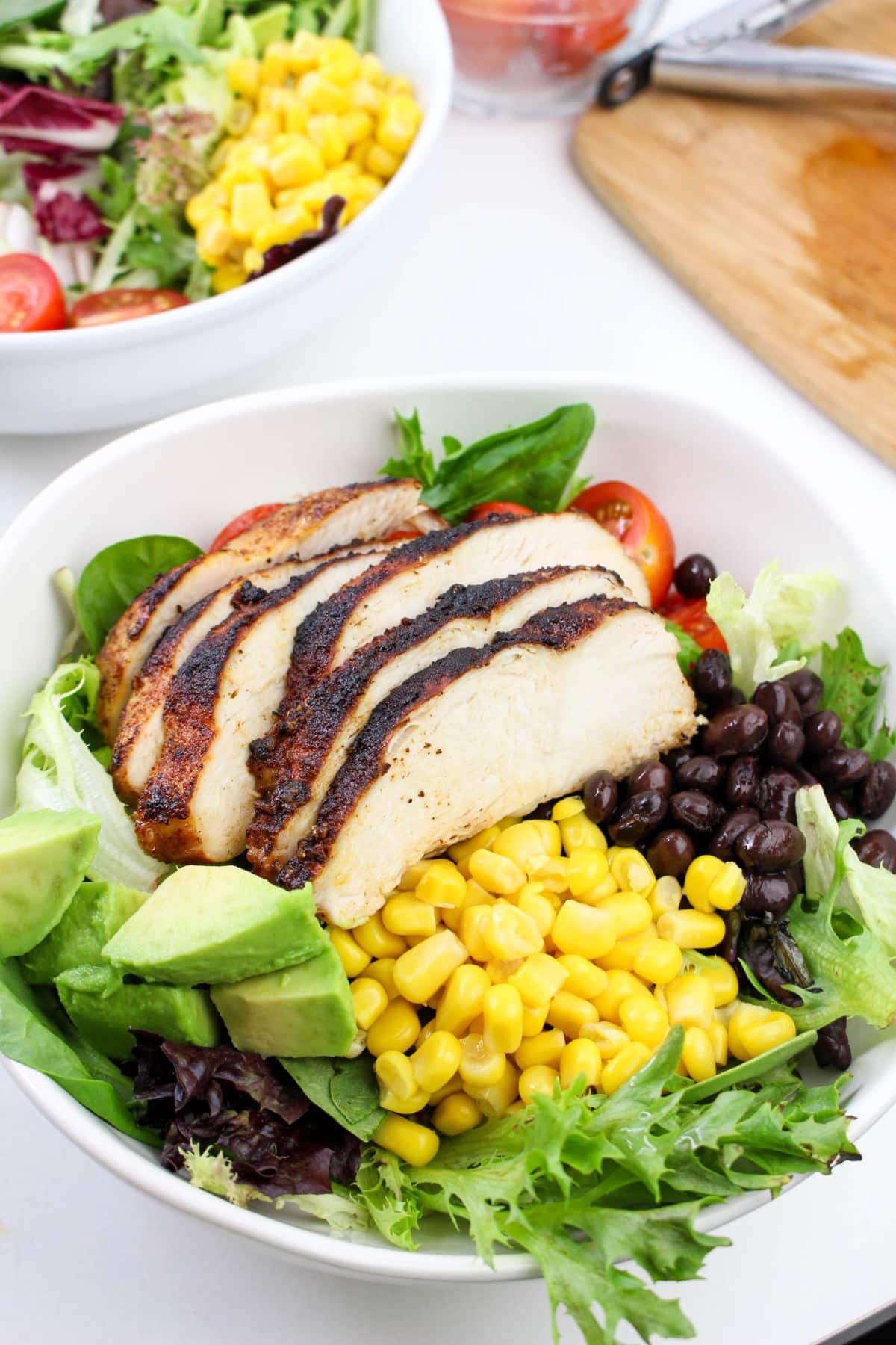 Chicken, mixed greens, black beans, corn, diced avocado, cherry tomatoes, and chopped cilantro in a large salad bowl