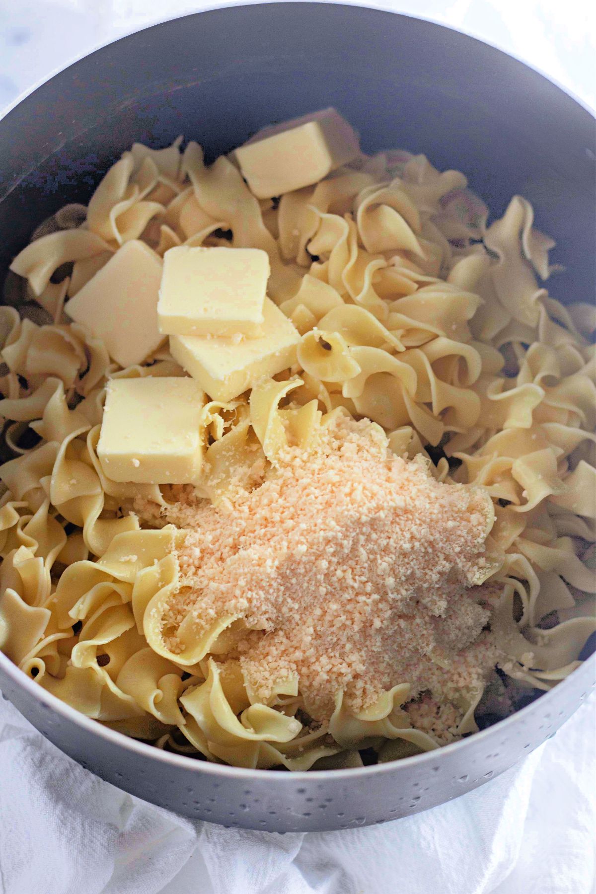 Butter, parmesan cheese and noodles in a pot.