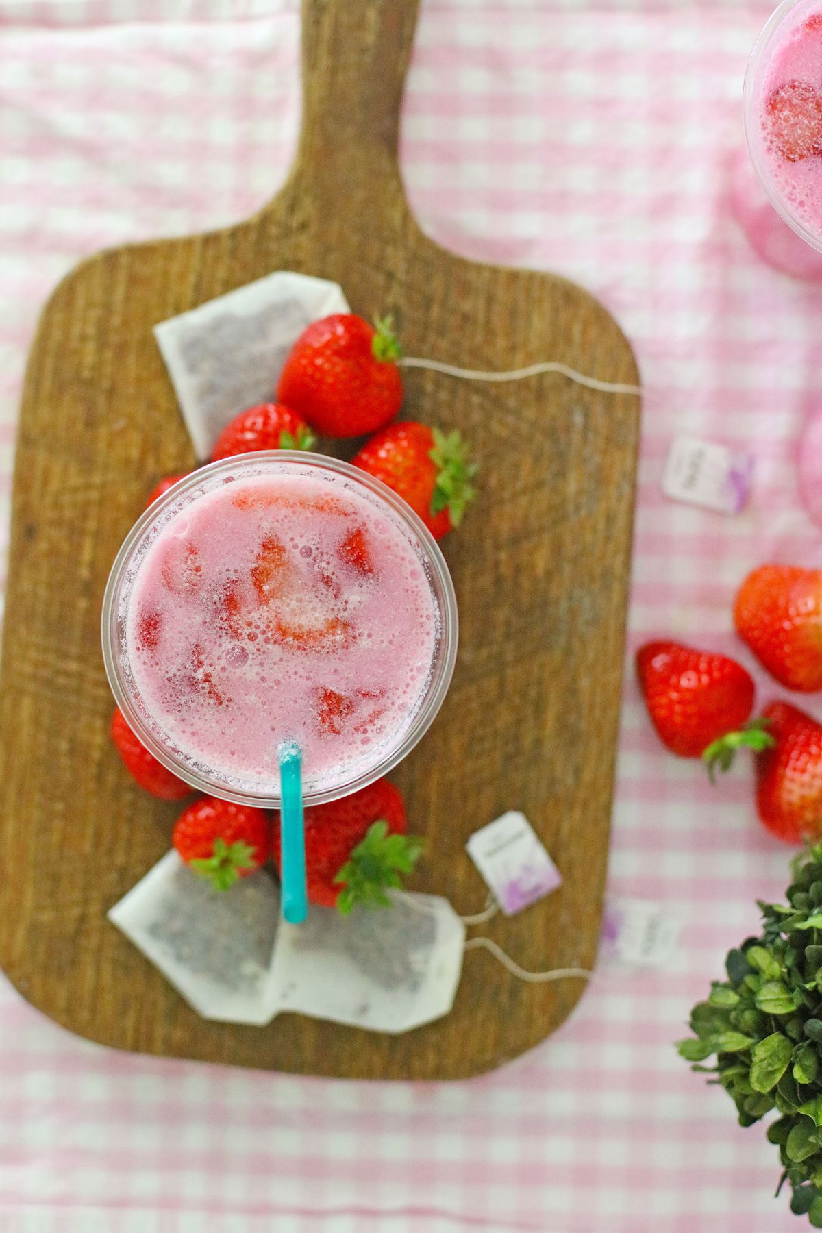 Overhead shot of pink drink with a straw on a cutting board.