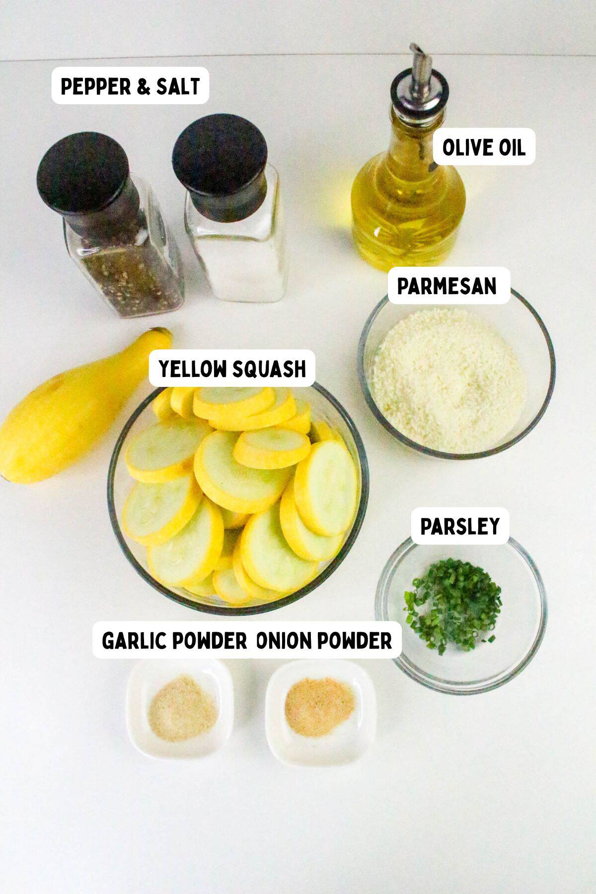 A flat lay of ingredients labeled: pepper & salt, olive oil, parmesan cheese, yellow squash slices in a bowl, chopped parsley, garlic powder, and onion powder in small dishes.