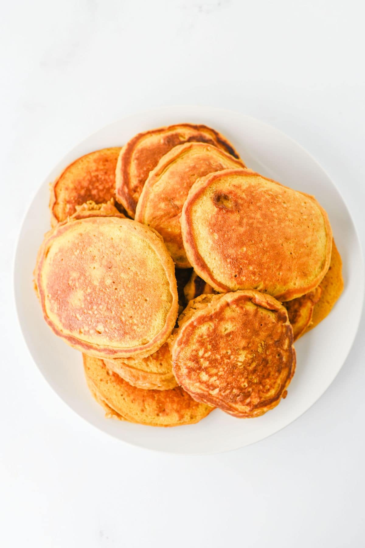A stack of golden-brown pancakes on a white plate.
